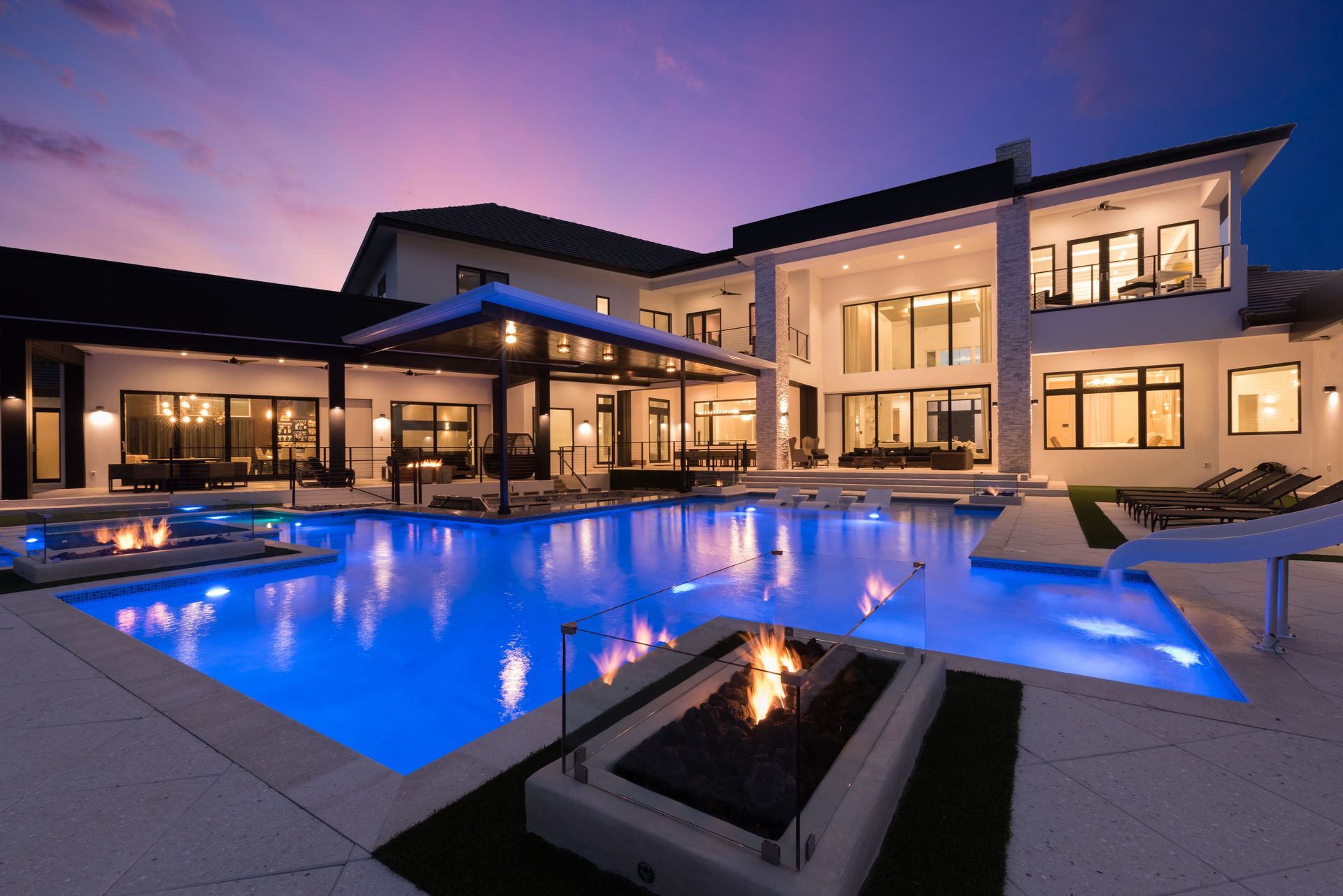 Luxury twilight pool exterior with fire features